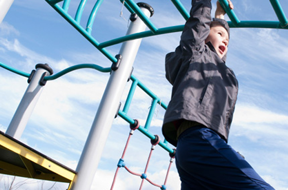Boy swinging on a climbing frame